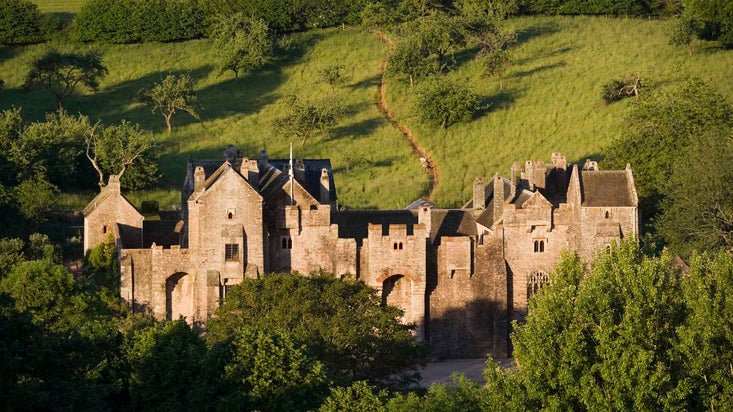 A distant view of the north front side of Compton Castle, Devon with fields behind